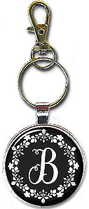 Striking black and white design is featured on this necklace or keychain with any initial centered in the white floral wreath.